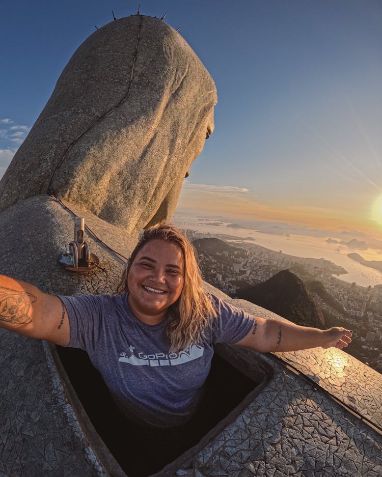 Woman Standing On Top Of The Christ The Redeemer Statue In Rio De Janeiro, Brazil 