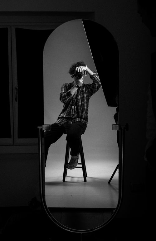 Free A creative black and white shot of a man photographing his reflection in a studio. Stock Photo