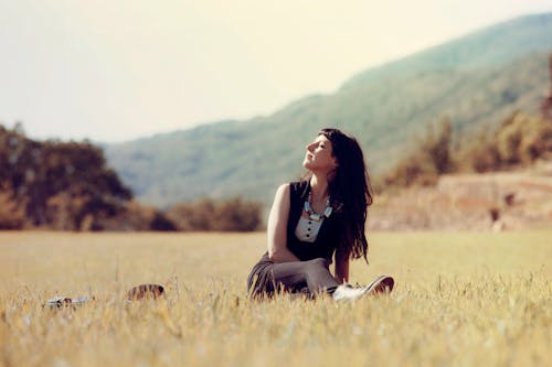 Woman Sitting on Green Grass Field Focus Photography