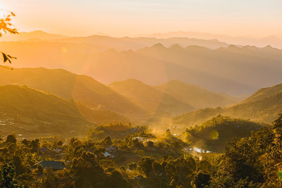 Valley illuminated by rising sun through mist