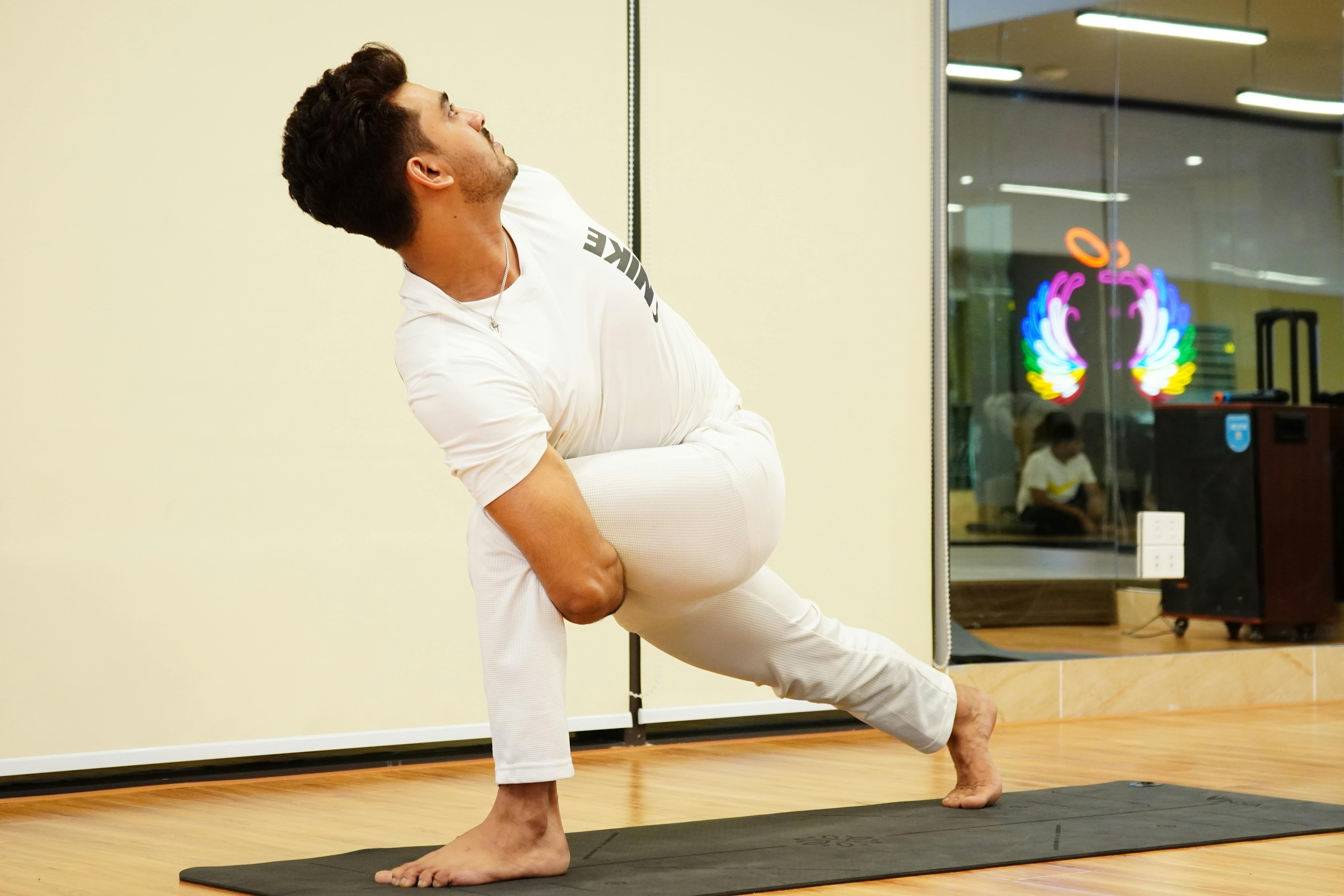Man engaging in yoga for mindfulness and flexibility, showcasing muscular strength on a yoga mat indoors.