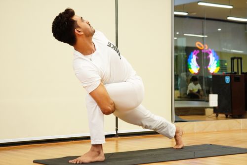 Free Man engaging in yoga for mindfulness and flexibility, showcasing muscular strength on a yoga mat indoors. Stock Photo