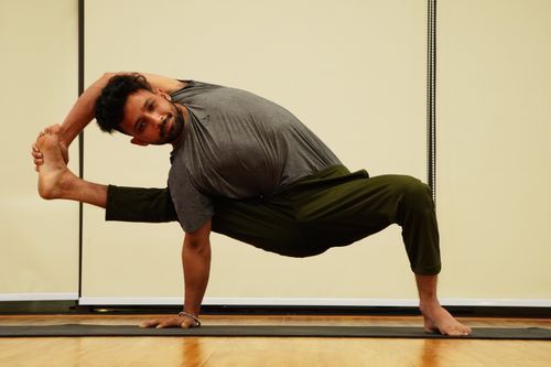Free A man demonstrates a challenging yoga pose indoors, displaying flexibility and control. Stock Photo