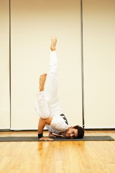 Man performing a yoga headstand on a mat indoors, showcasing strength and balance.