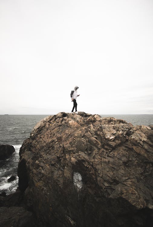 Free Man Standing on a Rock by the Sea Stock Photo