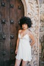 一个穿着白色连衣裙的女人站在一扇设计复杂的木门旁的时尚肖像