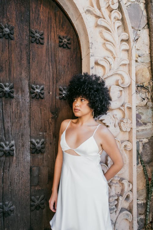 Young Woman in a White Dress Standing in front of Ornate Door 