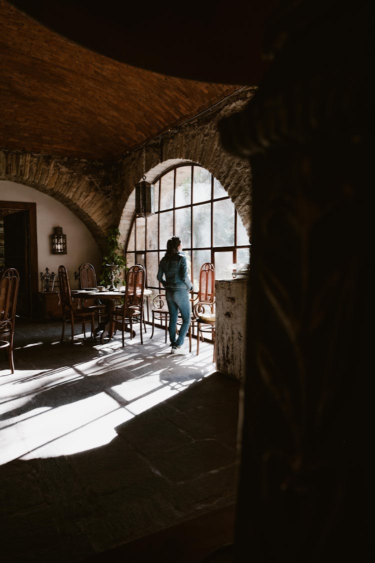 Woman Looking Through A Window In An Empty Cafe