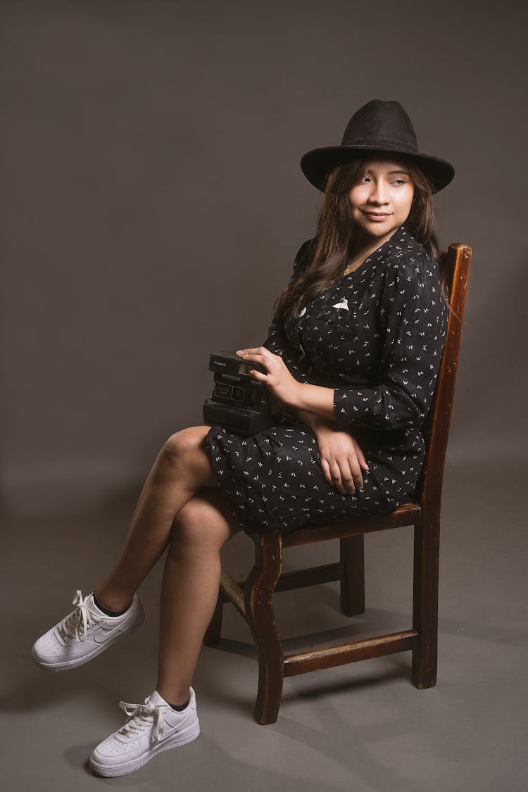 Woman In Hat Sitting With Camera On Chair