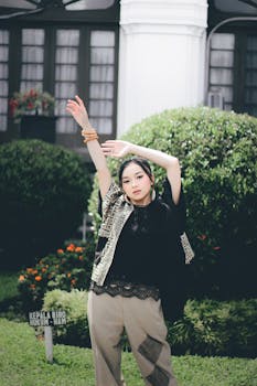 A young woman in stylish attire poses gracefully in a Bandung park, Indonesia.