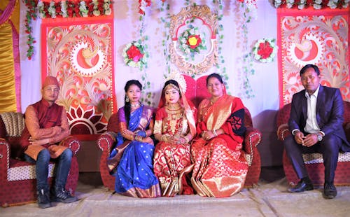 Men and Women Wearing Traditional Clothing Posing against a Decorative Wall