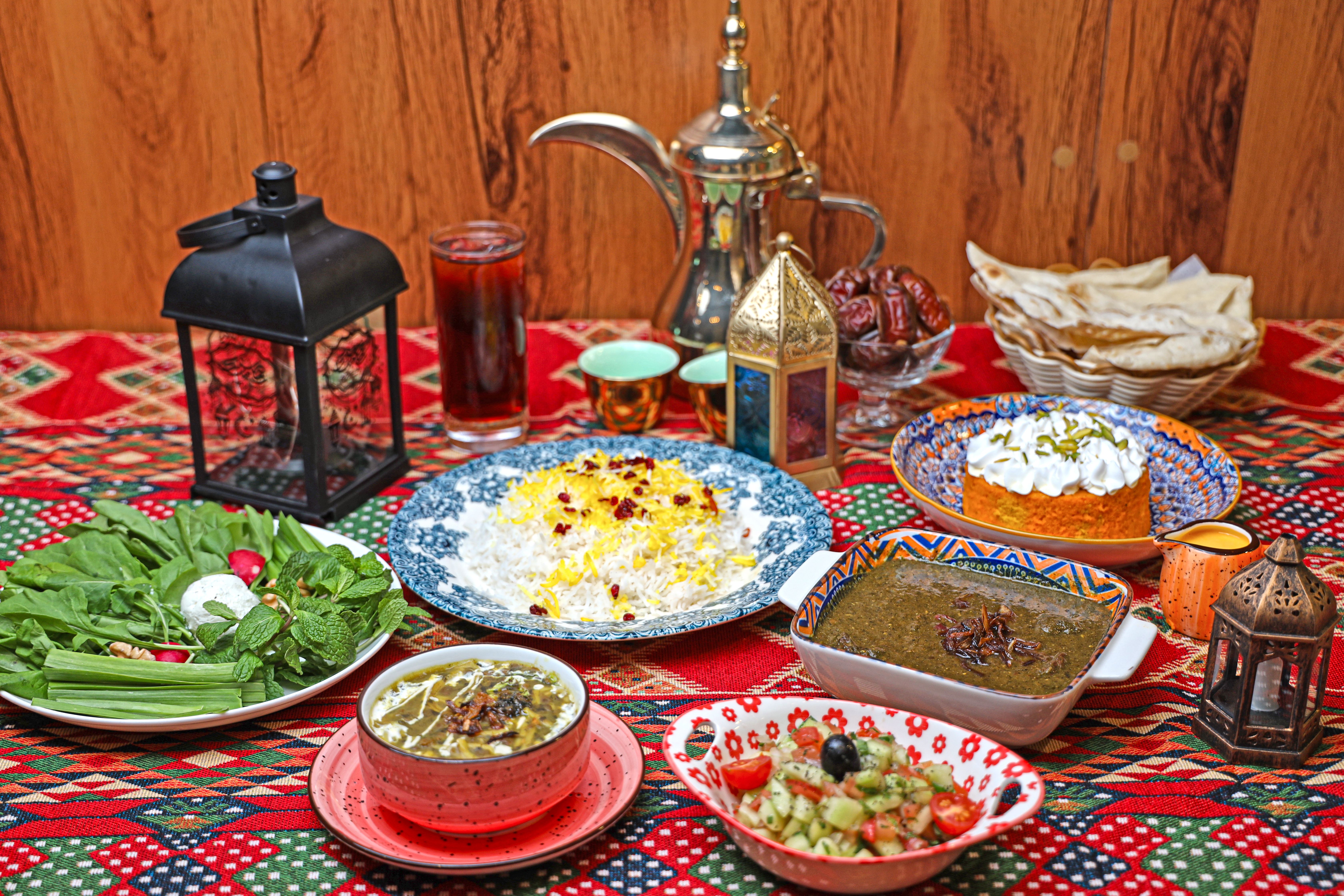A traditional Middle Eastern feast with rice, stew, and appetizers on a decorative table setting.