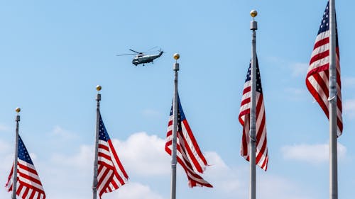 Helicopter Flying over a Row of Flagpoles with American Flags