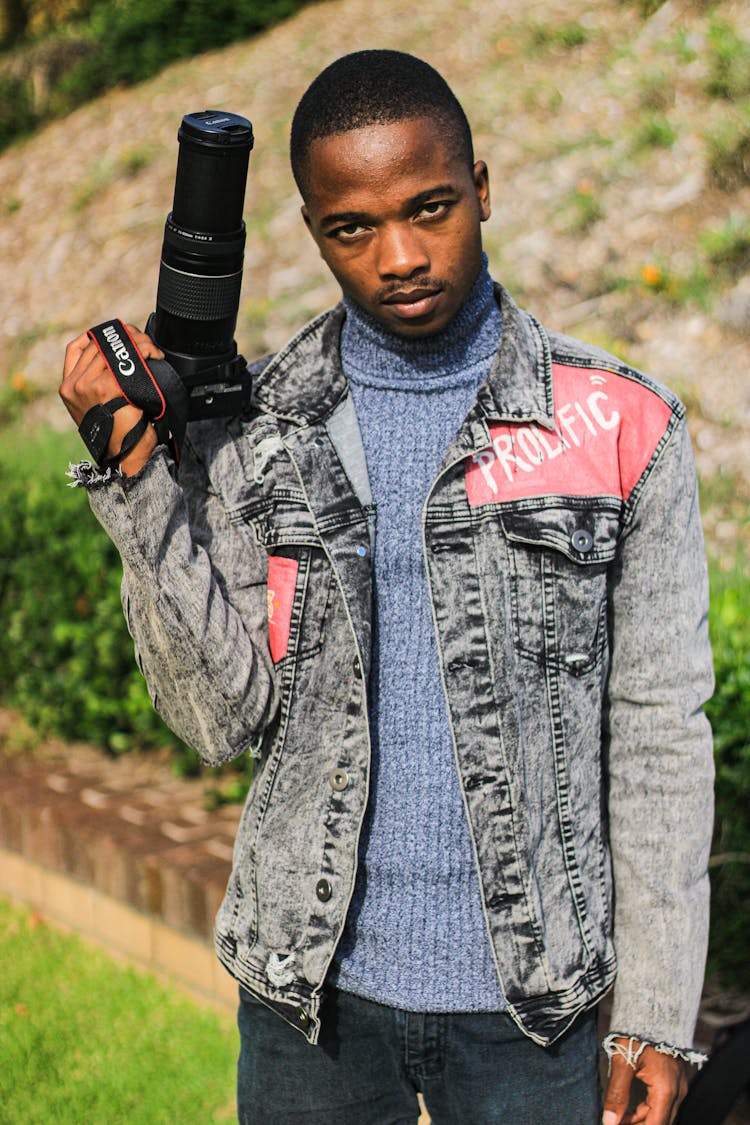 Photo Of A Young Man Holding A Camera With A Long Zoom