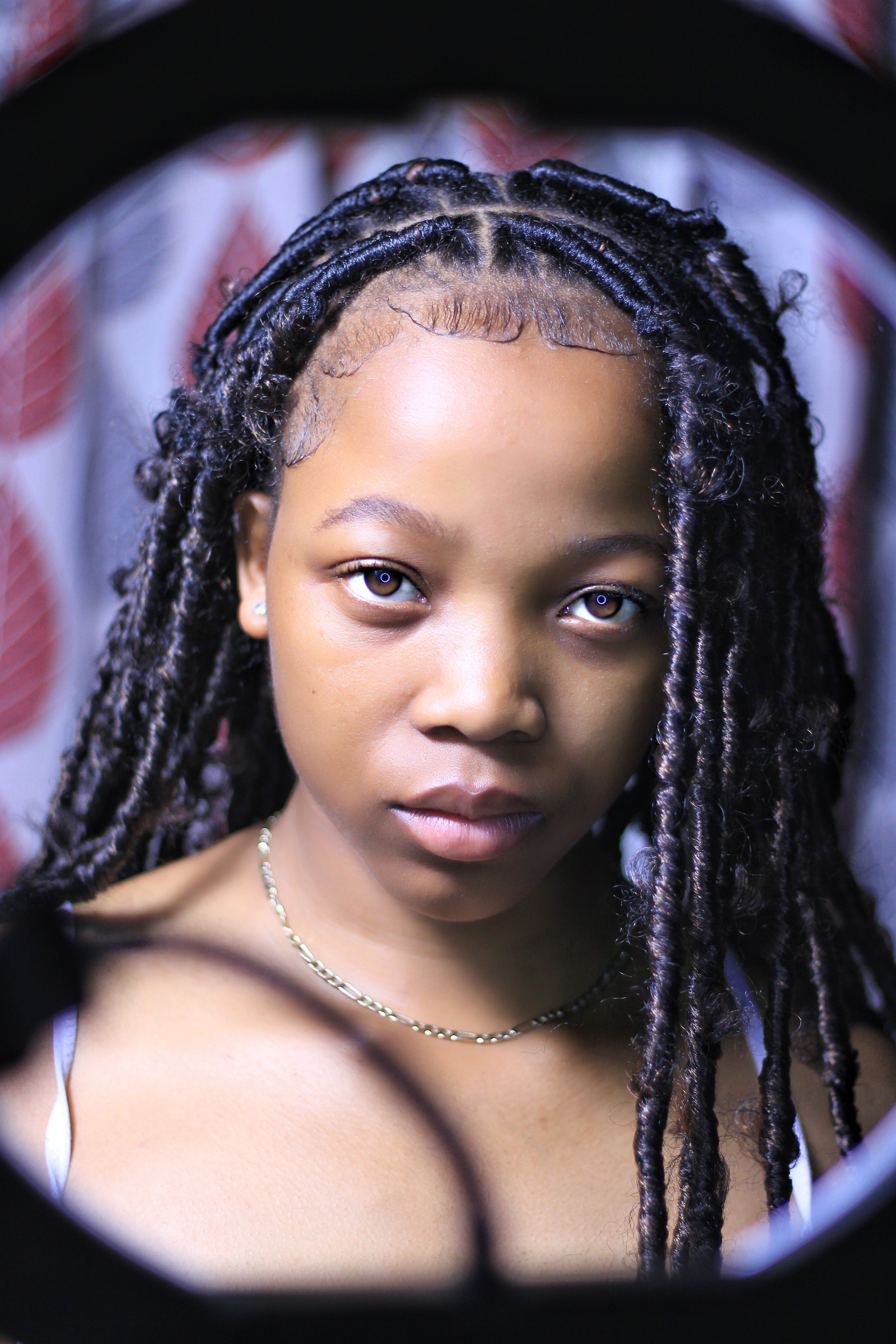 Close-up portrait of a young woman with braided hair looking straight at the camera.