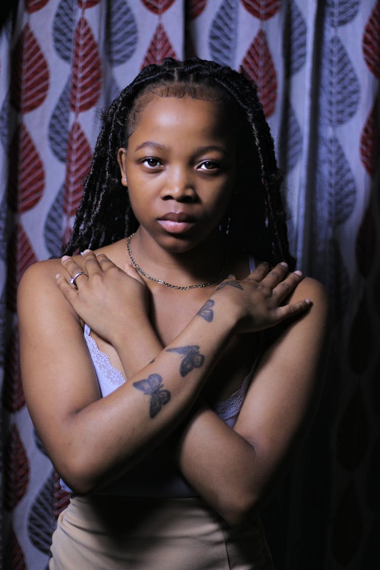 Young Woman With Tattoos Standing With Her Arms Crossed On Her Chest 