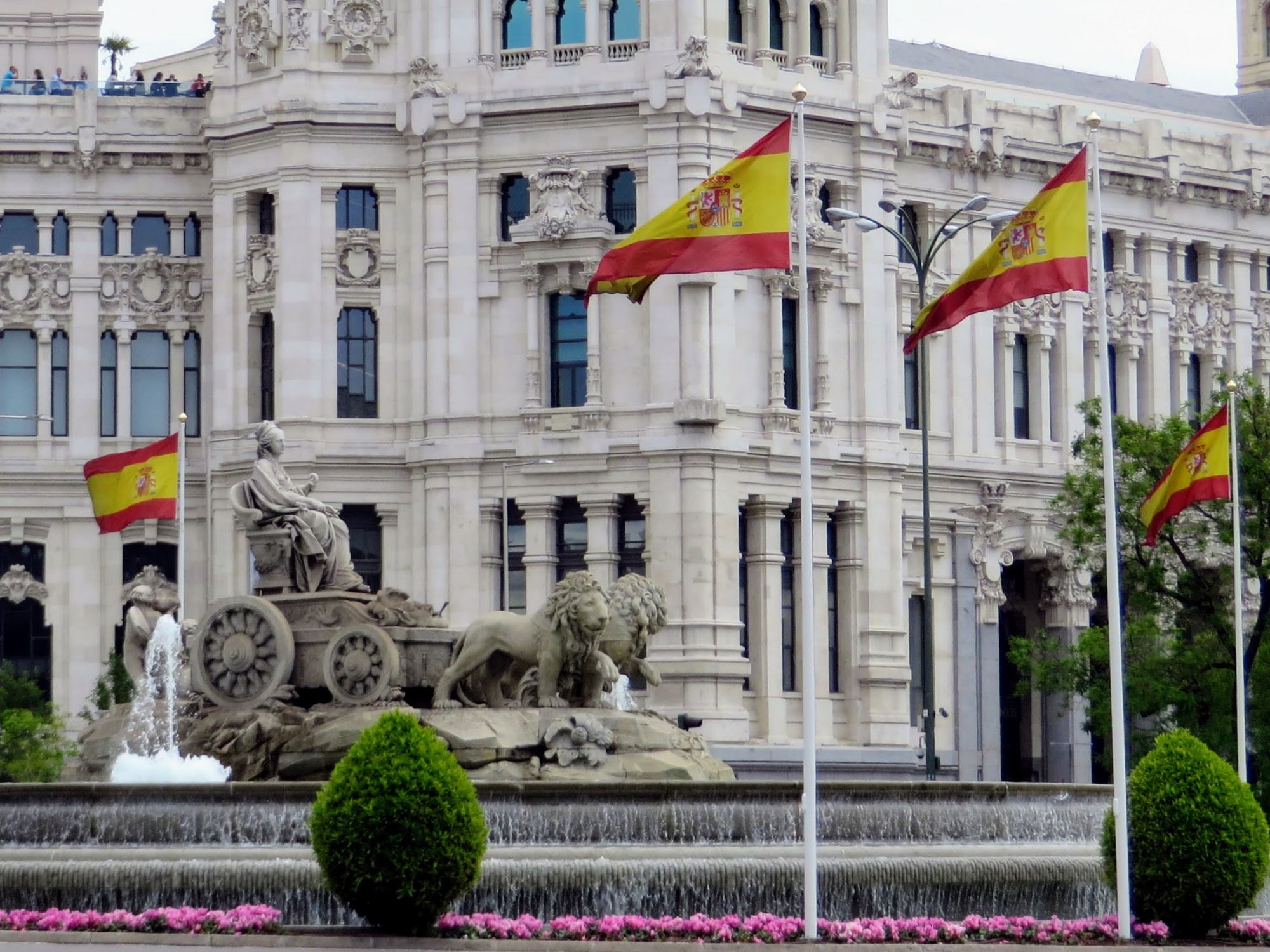 Multitud con banderas de España reunida de noche en la Plaza de Cibeles de Madrid