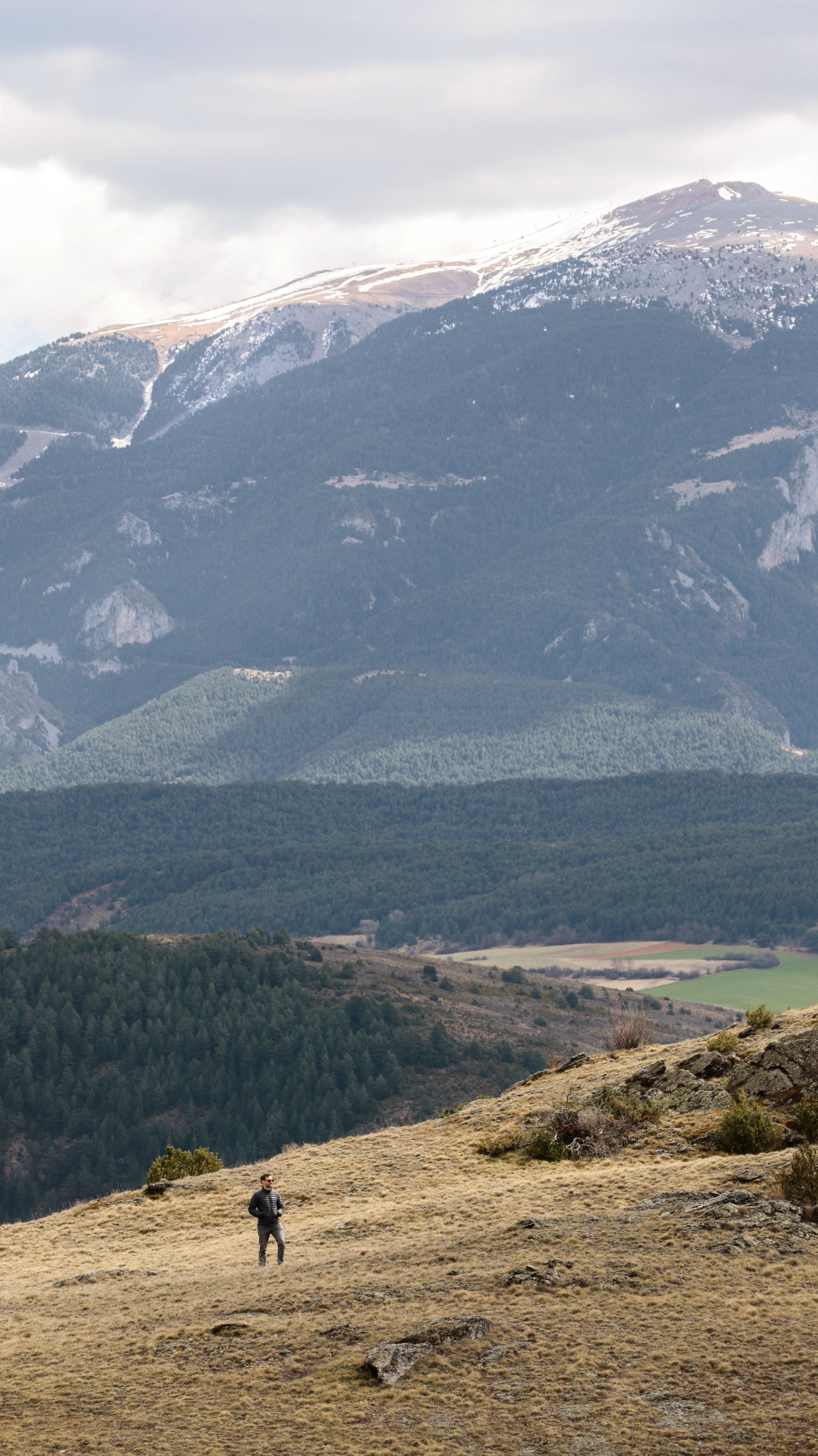 A lone hiker explores a vast mountain range with breathtaking views and serene solitude.