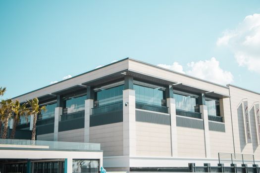 Contemporary shopping mall exterior with glass facade under clear blue sky.
