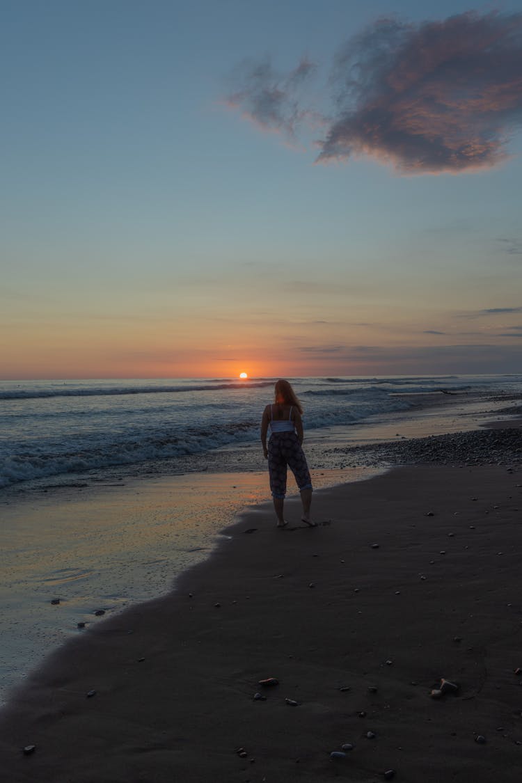 Woman Standing On The Beach At Sunset 