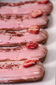 Close-up of strawberry-glazed eclairs adorned with sliced strawberries. Ideal for dessert inspiration.