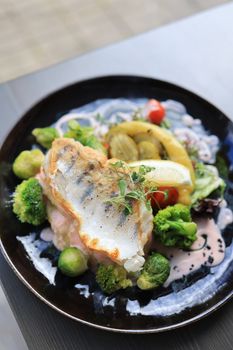 A beautifully plated gourmet fish dish with fresh vegetables and creamy sauce.