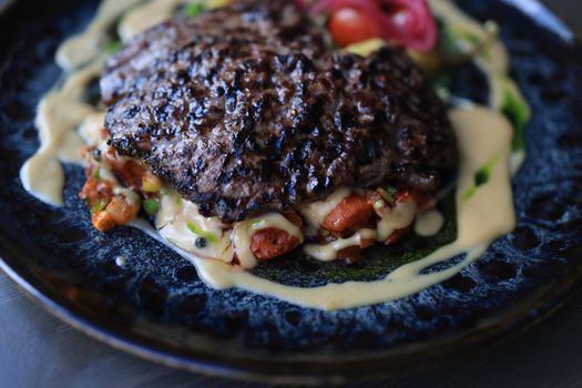 Savor the sight of roasted beef with creamy sauce, presented elegantly on a dark ceramic plate.