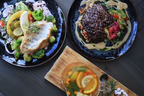Free Top view of gourmet fish and steak dishes with fresh citrus and herbs on a stylish table setting. Stock Photo