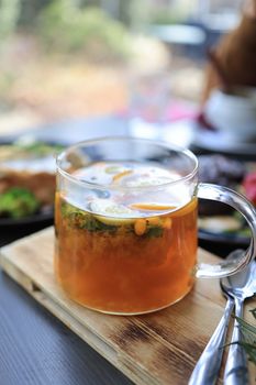Glass cup of herbal tea with citrus and herbs, perfect for a healthy lifestyle.