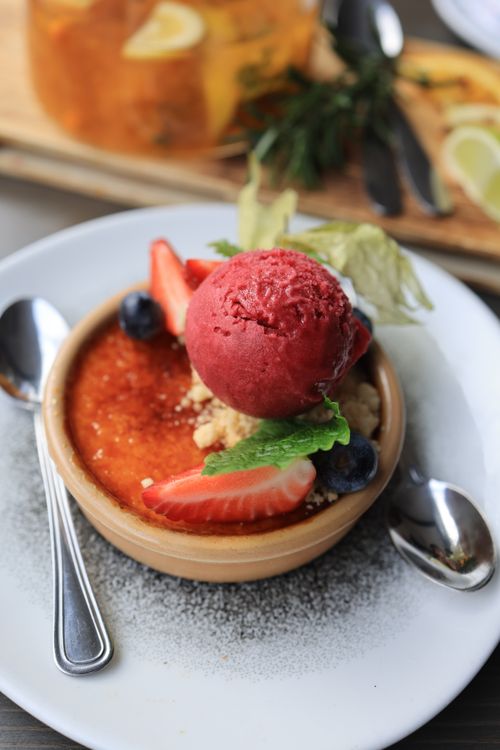 Free A close-up of a creme brulee topped with berry sorbet, strawberries, and blueberries. Stock Photo