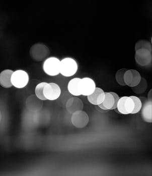 Abstract black and white bokeh with blurred lights and lens flare, creating a dreamy effect.