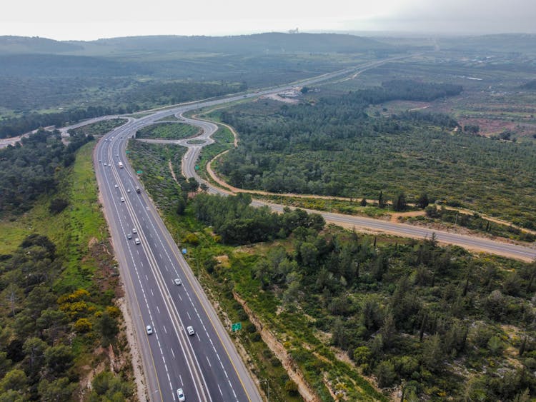 Aerial View O A Highway Curve Among Hills And Forest