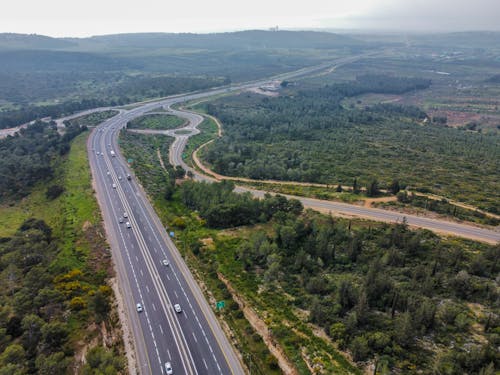 Free Aerial View o a Highway Curve among Hills and Forest Stock Photo
