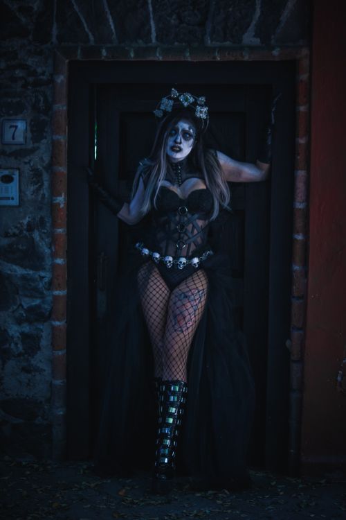 Free Woman in Día de Muertos costume with painted face, standing in a dark doorway. Stock Photo
