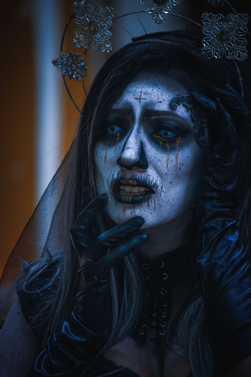 Dramatic portrait of a gothic woman with painted face and dark veil in fantasy makeup.