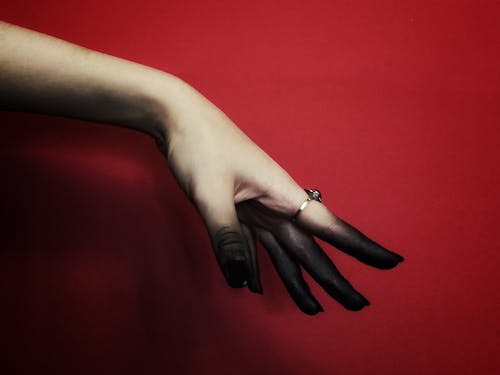 Womans Hand with a Ring on the Index Finger on Red Background
