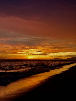 Beautiful sunset over Barra da Tijuca beach with golden hues and gentle waves.
