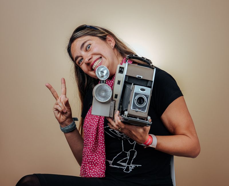 Happy woman holding vintage camera with a peace sign, capturing a nostalgic vibe. Happy woman holding vintage camera with a peace sign, capturing a nostalgic vibe.