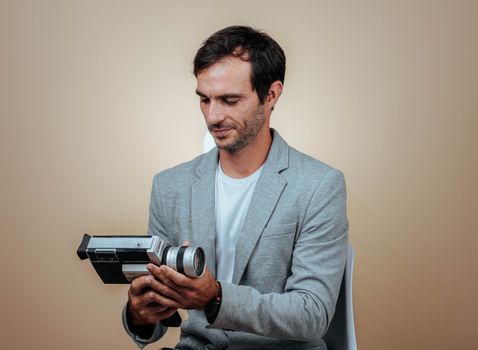 A man in a grey suit examining a vintage camera in a studio setting.