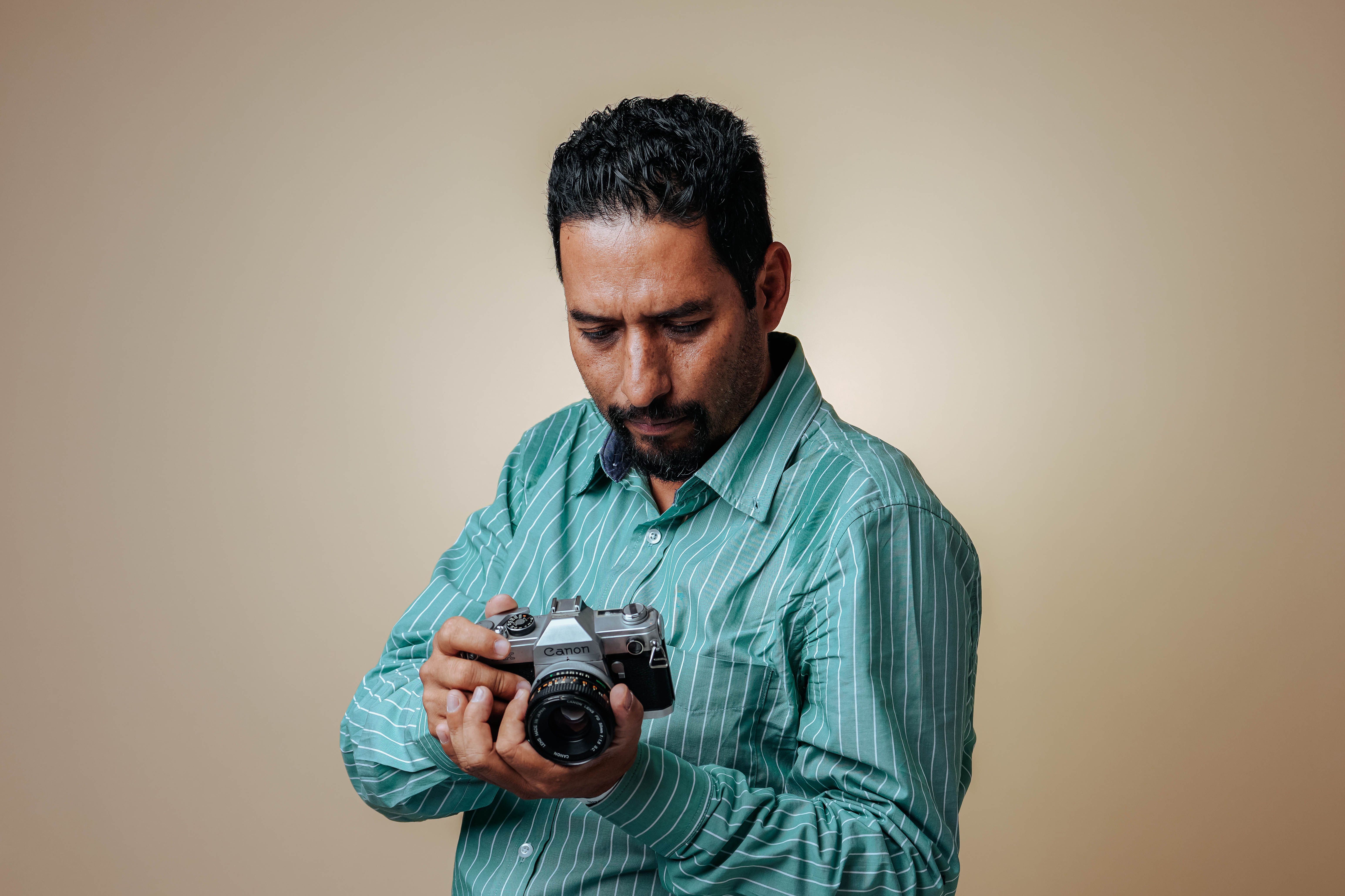 Man with a Mustache Looking Down at a Camera · Free Stock Photo