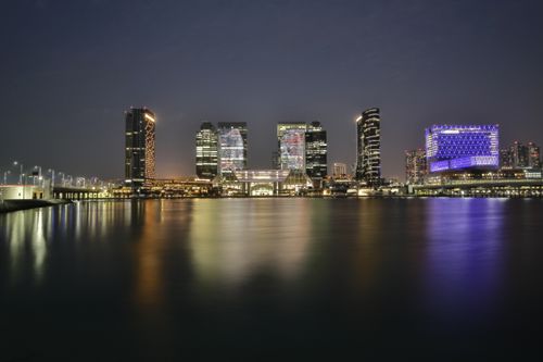 Free Illuminated city skyline reflecting on a calm river at night, showcasing modern architecture. Stock Photo
