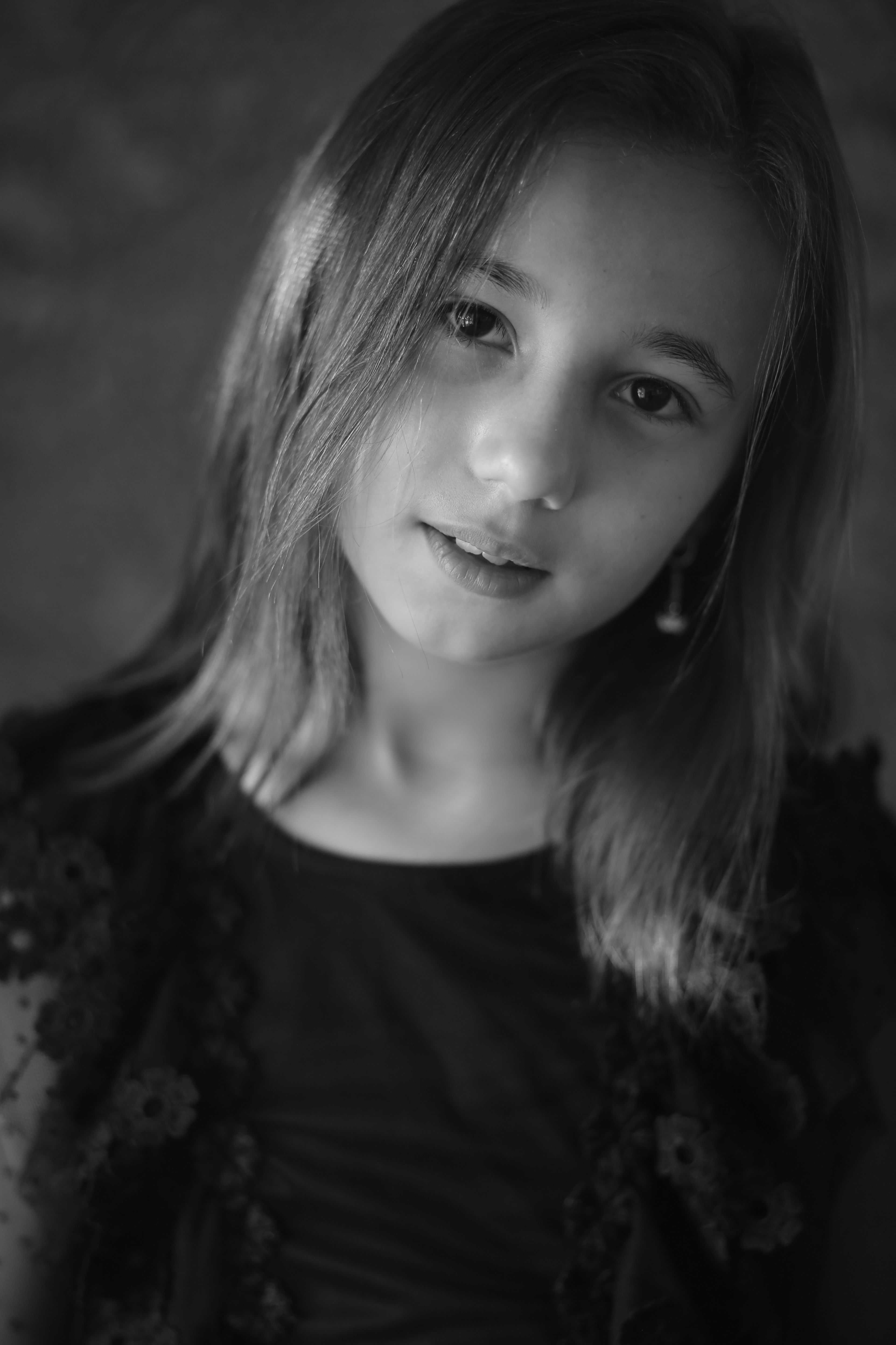 Captivating black and white portrait of a young girl with long hair posing indoors.