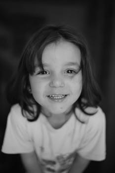 Charming black and white portrait of a smiling child with long hair.