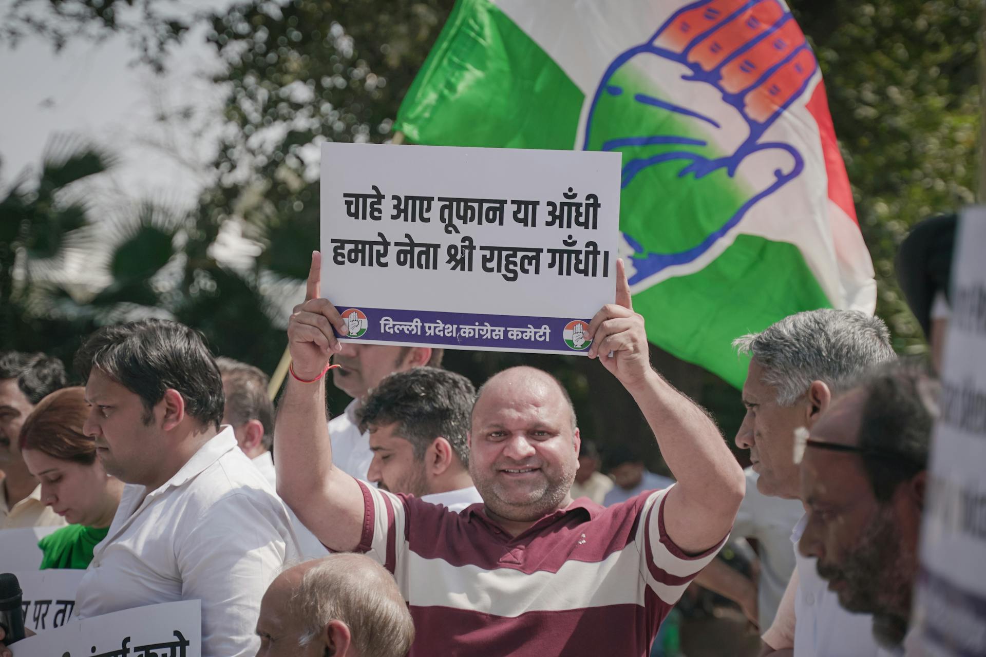 Crowd holding a political banner with a flag at a demonstration in India.