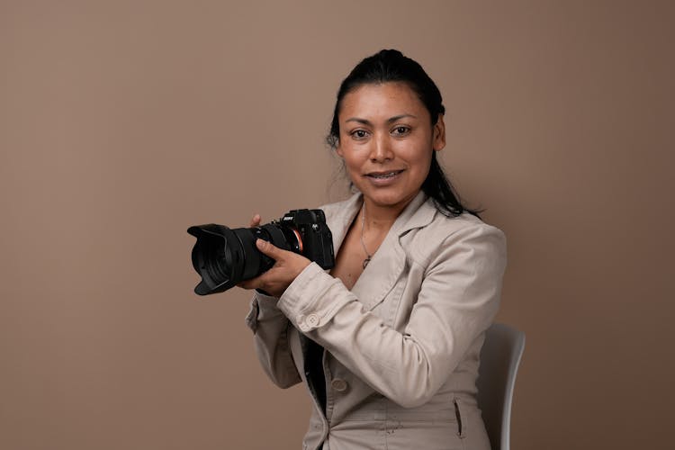 Woman With Professional Camera Posing In Studio