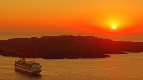 Free Cruise Ship Traveling on Body of Water Near Island during Golden Hour Stock Photo