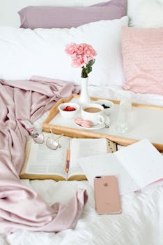 A serene scene of breakfast in bed with coffee, flowers, and books, perfect for relaxation.