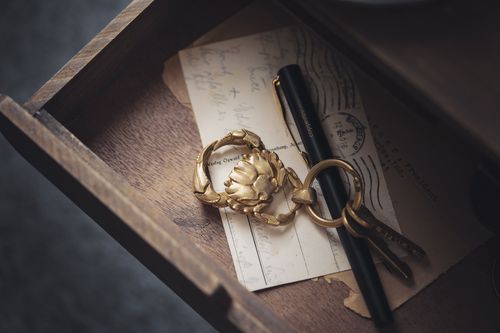 Free A high-angle view of a golden crab keychain, pen, and vintage postcards inside a wooden drawer. Stock Photo