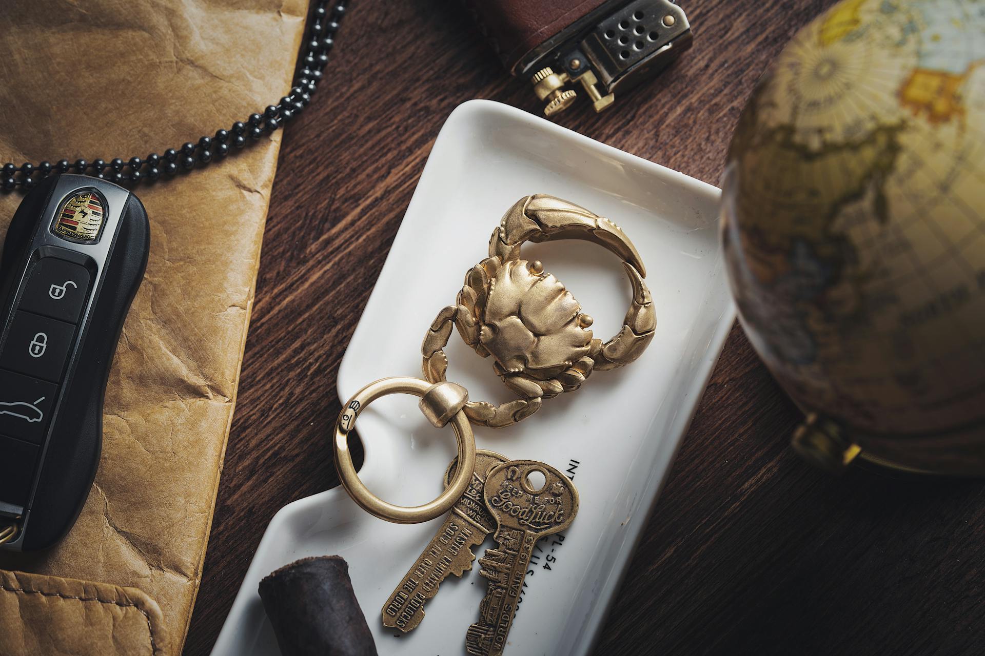 A golden crab-themed keychain on a tray with keys, surrounded by luxury accessories and décor.