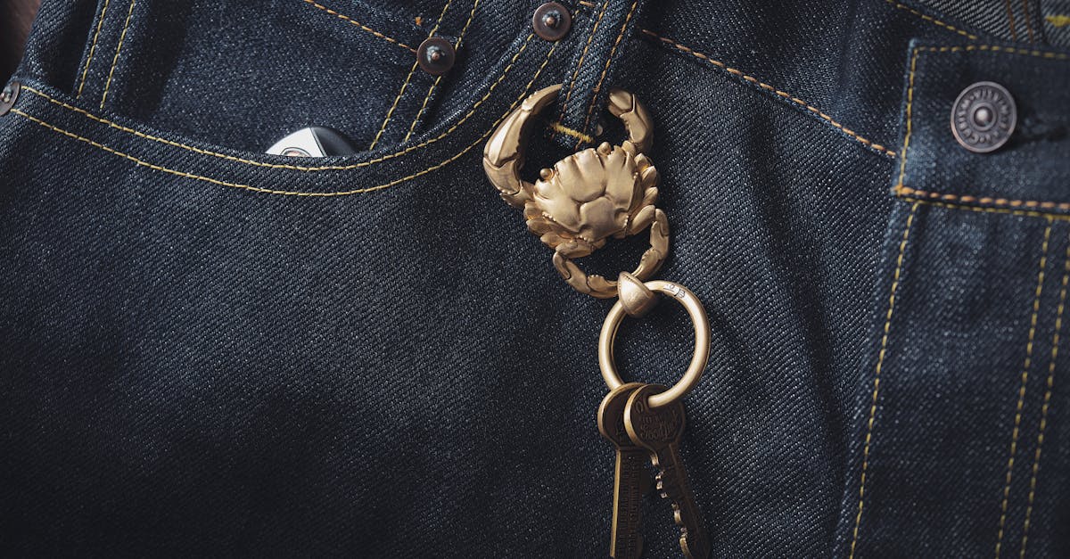 A close-up view of a golden crab keychain hanging from denim jeans. Stylish and unique accessory.
